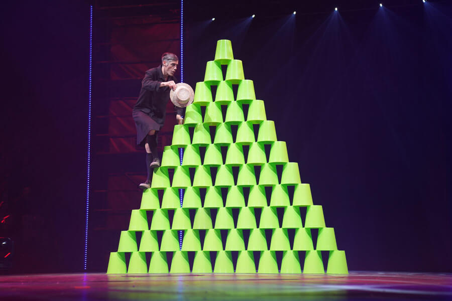 Ein Mann besteigt eine Pyramide, gebaut aus grünen Eimern.